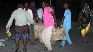 epa04841305 People carry the body of a person killed in an attack in front of a hotel in Mogadishu, Somalia, 10 July 2015. Reports say the heavy gunfire followed explosions at Wehliya hotel in Mogadishu, killing at least 4 people. Somalia's Islamist militant group al-Shabab has claimed responsibility for the latest attack. EPA/SAID YUSUF WARSAME +++(c) dpa - Bildfunk+++