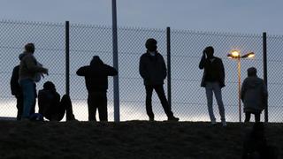 Migrants are seen in silhouette as they stand on a rise near a fence as they gather near the Channel Tunnel access in Frethun, near Calais, France, July 30, 2015. Migrants who massed around the entrance to the Channel Tunnel said on Thursday they would keep trying to sneak across to Britain, undaunted by the arrival of 120 extra riot police on the French side. A police officer said the number of migrants trying to enter Britain eased slightly overnight compared to earlier in the week, with about 800 migrants around the site and some 300 intercepted by police. REUTERS/Pascal Rossignol