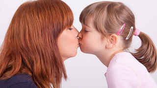 Die junge Mutter gibt ihrer Tochter einen Kuss