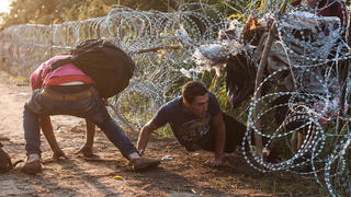 dpatopbilder epa04899968 Illegal migrants helped each other through the razor wire fencing at the border between Hungary and Serbia near Roszke, 180 kms southeast from Budapest, Hungary, 27 August 2015. EPA/Sandor Ujvari HUNGARY OUT (re-cropped version) +++(c) dpa - Bildfunk+++