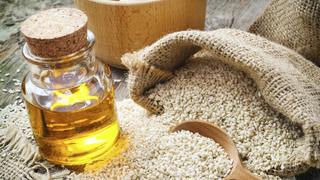 sesame seeds in sack and bottle of oil on wooden rustic table