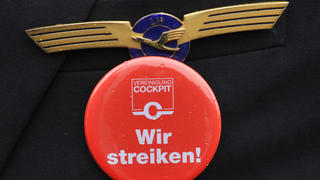 ARCHIV - Einen roten «Wir Streiken!»-Button trägt ein Lufthansa-Pilot am 22.02.2010 am Flughafen in Frankfurt am Main (Hessen) während einer Protestkundgebung. Foto: Boris Roessler/dpa (zu dpa "Piloten streiken am Dienstag bei der Lufthansa" vo9m 07.09.2015) +++(c) dpa - Bildfunk+++