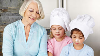 Zwei Kinder kochen zusammen mit der Oma zu Weihnachten
