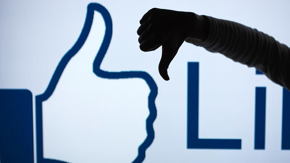 FILE - ILLUSTRATION - A woman makes the 'thumbs down' sign with her fist and thumb in front of an enlarged 'Like' symbol of the social netweorking site Facebook in Schwerin, Germany, 04 April 2013 (STAGED PICTURE). Photo: Jens Buettner/dpa (zu dpa "Z