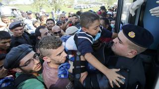 A Croatian policeman helps a boy as migrants board a bus in Tovarnik, Croatia, September 17, 2015. The European Union's migration chief Dimitris Avromopoulos rebuked Hungary on Thursday for its tough handling of a flood of refugees as asylum seekers thwarted by a new Hungarian border fence and repelled by riot police poured into Croatia, spreading the strain. REUTERS/Antonio Bronic