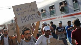 Migrants hold banners as they protest at the Tovarnik railway station, Croatia September 18, 2015. Migrants continued to stream through fields from Serbia into the European Union on Friday, undeterred by Croatia's closure of almost all road crossings after an influx of more than 11,000. Helpless to stem the flow, Croatian police rounded them up at the Tovarnik on the Croatian side of the border, where several thousand had spent the night under open skies. Some kept travelling, and reached Slovenia overnight. REUTERS/Antonio Bronic