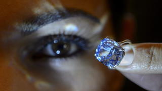 epa05010385 A Sotheby's employee displays the rare Blue Moon Diamond during a preview at the Sotheby's, in Geneva, Switzerland, 04 November 2015. The 12.03 carat blue diamond is the largest cushion shaped fancy vivid blue diamond to ever appear at auction. It is estimated to sell between 35-55 million US dollars. The auction will take place in Geneva, on 11 November. EPA/MARTIAL TREZZINI +++(c) dpa - Bildfunk+++