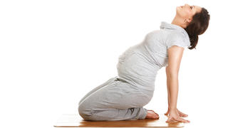 Pregnant woman doing gymnastic exercises on isolated white background