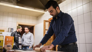 Der aus Syrien stammende Kawa Suliman (r) bereitet am 17.12.2015 in Zapfendorf (Bayern) syrisches Brot zu. Der 30-jährige syrische Anwalt Suliman bewirtete vor einigen Monaten zusammen mit anderen Asylbewerbern zwei Ausflügler, die nicht wussten, dass der ehemalige Gasthof mittlerweile als Asylunterkunft dient. Foto: Nicolas Armer/dpa (zu dpa/lby "Asylbewerber bewirtet Ausflügler - Frau zu Tränen gerührt" vom 18.12.2015) +++(c) dpa - Bildfunk+++