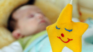 Pssst...Ruhe...Ein zehn Wochen alter Säugling schläft, im Vordergrund eine gelbe Spieluhr in Sternform, aufgenommen am 17.09.2009 in Straubing (Niederbayern). Foto: Armin Weigel dpa/lby +++(c) dpa - Report+++