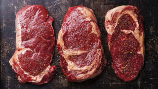 Three cuts of Raw fresh meat Steaks and seasonings on dark background