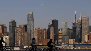 epa04166486 A photograph made available on 13 April 2014 shows the moon rising behind the skyline of New York City as a people ride their bikes along the Hudson River in Hoboken, New Jersey, USA, 12 April 2014. People were making the most of the warm spring weather in the city, as mixed conditions with light rain and lower temperatures are forecasted for the area in the coming days. EPA/GARY HERSHORN +++(c) dpa - Bildfunk+++