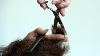 Ein Frisör schneidet einem Mann die Haare. Foto: Susann Prautsch/Archiv