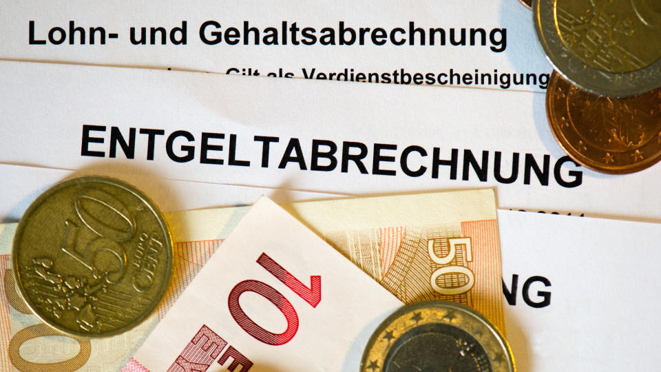 Lohn- und Gehaltsabrechnungen, darauf Euromünzen und -scheine