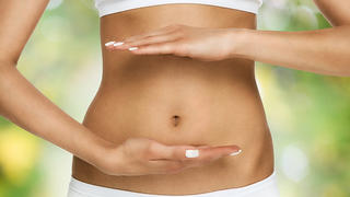 Pregnancy or diet concept, female hands protecting the stomach over nature background