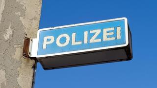 Blick auf das Hinweisschild einer Polizeiwache. Foto: Stefan Sauer/Archiv