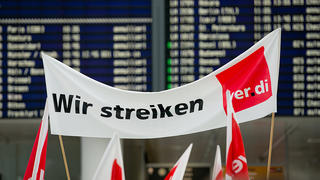 ARCHIV - Ein Banner mit der Aufschrift "Wir streiken" ist am 27.03.2014 während einer Demonstration im Rahmen eines Warnstreiks am Flughafen in München (Bayern) zu sehen.   Foto: Sven Hoppe/dpa    (zu dpa "Warnstreiks an Flughäfen: Verband verlangt zusätzliche Streikregeln" vom 26.04.2016) +++(c) dpa - Bildfunk+++