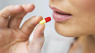 medicine, health care and people concept - close up of woman taking in pill