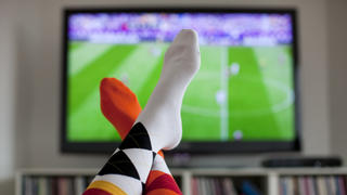 ARCHIV - ILLUSTRATION - Überschlagene Beine vor einem Fernsehgerät, auf dem ein Fußballspiel übertragen wird, aufgenommen am 13.06.2012 in Köln. Foto: Rolf Vennenbernd (zu dpa Fernsehen bestimmt die Freizeit vom 29.08.2013) +++(c) dpa - Bildfunk+++