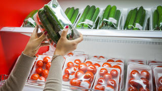Image of packaged cucumber with woman hand in the supermarket