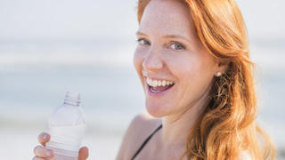 Portrait of woman drinking water on beach, Bildnis von Frau mit Trinkwasser am Strand Keine Weitergabe an Drittverwerter.