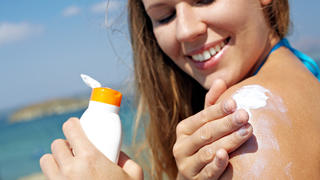 Young woman applying sunscreen 