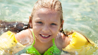 Cute little girl swimming with armbands in the sea.