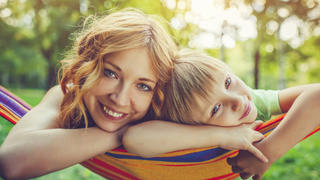 Mother and son in hammock in a park or back yard in summer