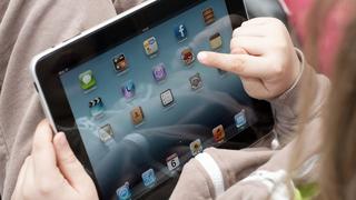 "St. Peter-Ording, Germany - January 6, 2013: Child in elementary school age is showing the iPad home screen in horizontal view. The young boy is pointing on the application ""Angry Birds""."