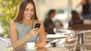 Girl texting on the smart phone in a restaurant terrace with an unfocused background