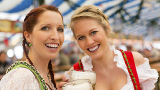 Young women in traditional Bavarian clothes - dirndl or tracht - on a festival or Oktoberfest in a beer tent