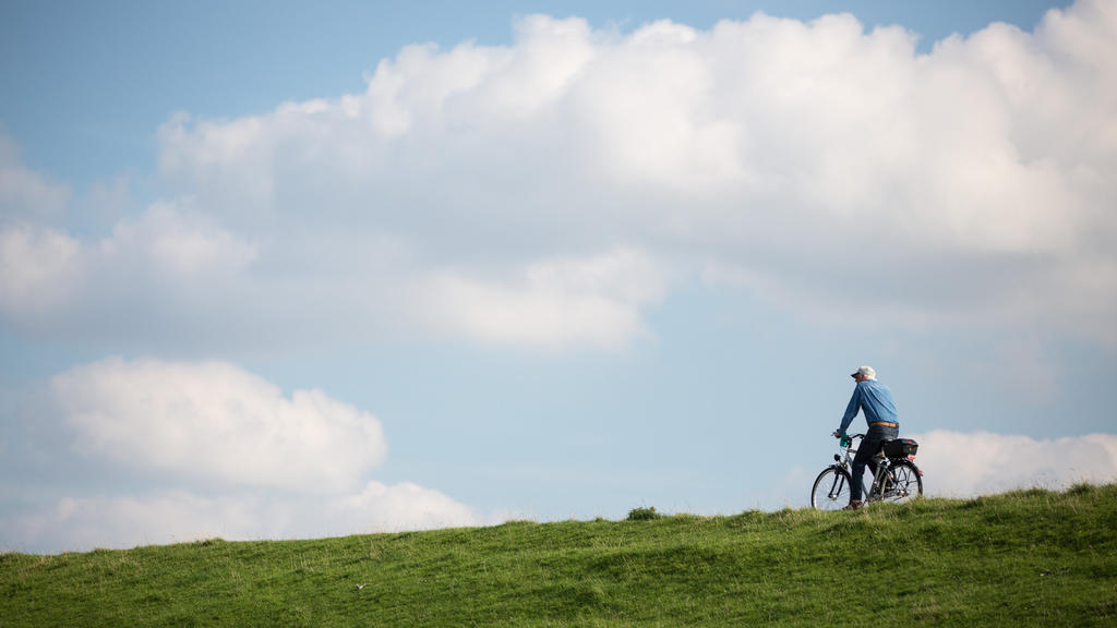 Ein Radfahrer fährt am 06.09.2016 bei Brunsbüttel (Schleswig-Holstein) bei strahlendem Sonnenschein auf dem Deich an der Elbe stromaufwärts. Foto: Christian Charisius/dpa +++(c) dpa - Bildfunk+++