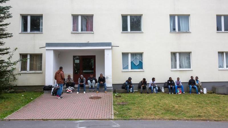 Flüchtlinge sitzen vor einem Wohnblock