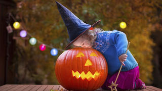 Little girl and boy carving pumpkin at Halloween. Dressed up children trick or treating. Kids trick or treat. Child in witch costume playing in autumn park. Toddler kid with jack-o-lantern.