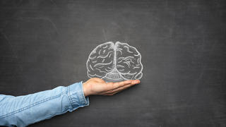 Brain and hand front of blackboard