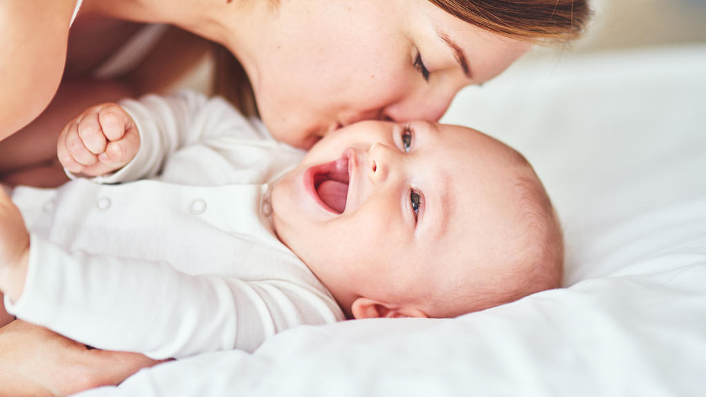 Mutter küsst ihr lachendes Baby