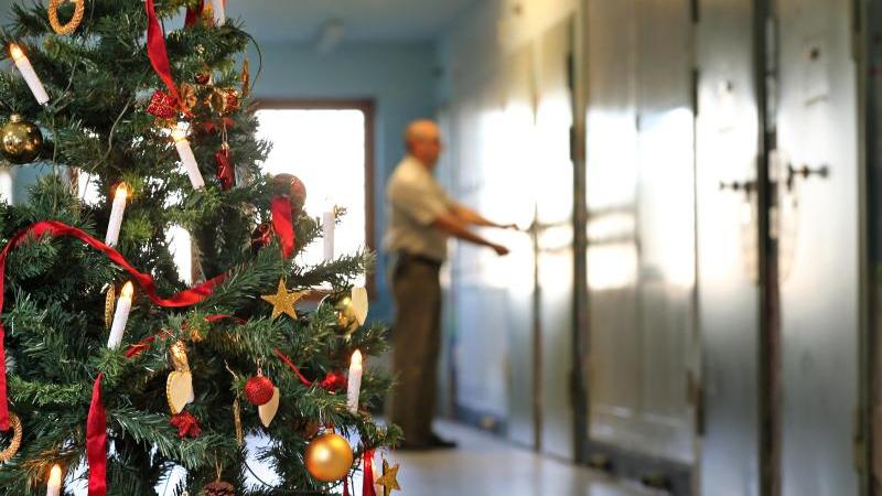 Hinter einem Weihnachtsbaum schließt ein Justizvollzugsbeamter eine Tür ab. Foto: Jan Woitas/Archiv