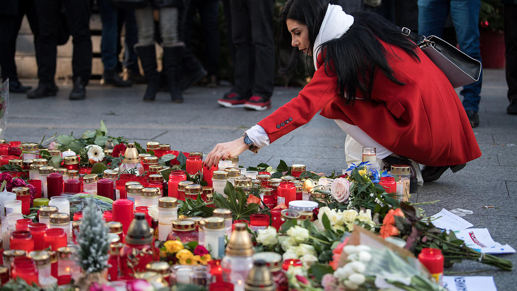 Eine trauernde Frau legt am 21.12.2016 am Anschlagsort auf dem Weihnachtsmarkt am Breitscheidplatz in Berlin Blumen nieder und zünden Kerzen an. Bei dem Anschlag mit einem Lastwagen auf den Weihnachtsmarkt an der Gedächtniskirche am Montagabend (19.1
