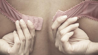 Hands of woman dressing pink brassiere