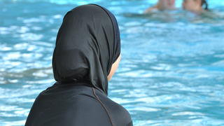 ARCHIV - Eine muslimische Schülerin sitzt am 23.06.2009 in einem Ganzkörper-Badeanzug (Burkini) am Rande eines Schwimmbeckens. Zwei muslimische Eltern aus Basel wehren sich vor dem Europäischen Menschenrechtsgerichtshof dagegen, ihre Töchter zum gemischten Schwimmunterricht zu schicken - ihr Glaube verbiete dies. Foto: Rolf Haid/dpa +++(c) dpa - Bildfunk+++