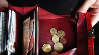 Zwei Hände halten ein Portemonnaie mit Geld. Foto: Andreas Gebert/Archiv