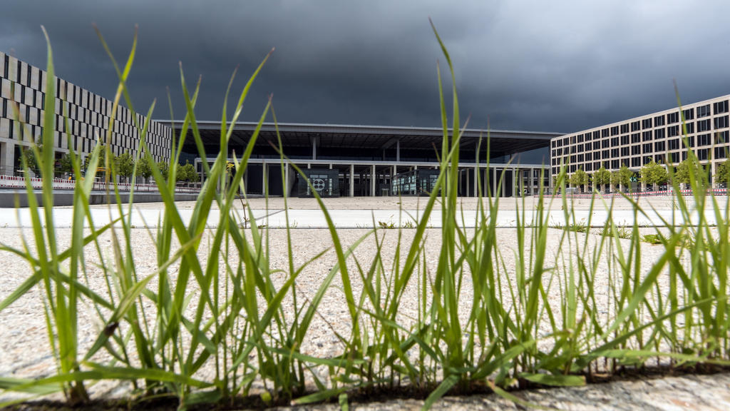ARCHIV - Gras wächst aus den Betonfugen am 14.06.2016 vor dem Terminalgebäude des Hauptstadtflughafens Berlin Brandenburg Willy Brandt (BER) in Schönefeld (Brandenburg). (zu dpa-KORR "BER 2017: Zu wenig Jahr für so viel Flughafen" vom 28.12.2016) Fot