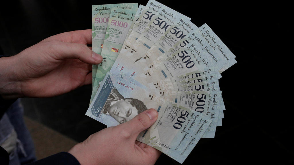 A man holds 500 and 5000 bolivar banknotes for a photo in Caracas, Venezuela January 16, 2017. REUTERS/Marco Bello