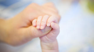 Parent hand holding baby's leg