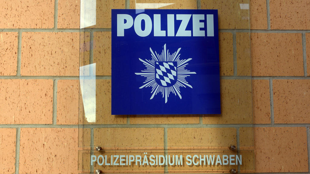ARCHIV - Eine Hinweistafel hängt am 11.02.2017 in Augsburg (Bayern) am Polizeipräsidium Schwaben Nord. In der dortigen Einsatzzentrale soll ein Polizist den Notruf eines Jugendlichen abgewimmelt haben. Der Polizist muss sich deswegen vor Gericht vera