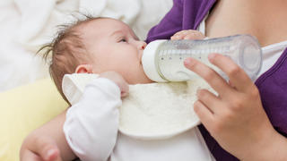Mother feeding baby with milk from a bottle.