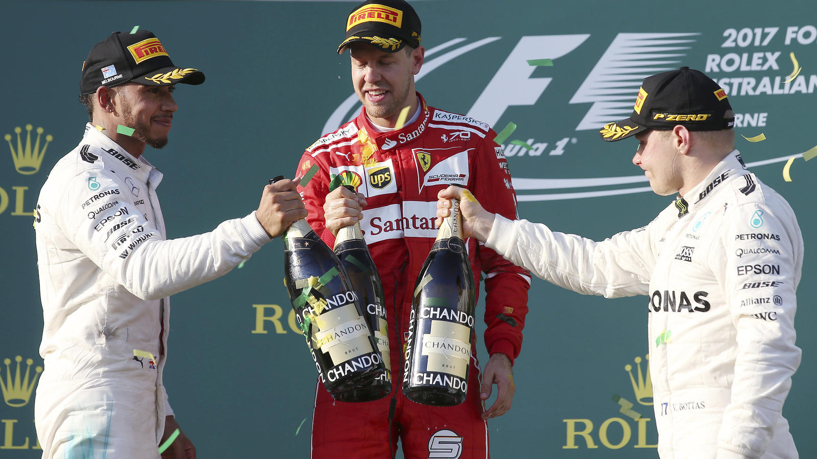 Motorsport: Formel-1-Weltmeisterschaft, Grand Prix von Australien, am 26.03.2017 in Melbourne (Australien). Der Deutsche Sebastian Vettel (M) vom Team Scuderia Ferrari steht nach seinem Sieg mit dem zweitplatzierten Briten Lewis Hamilton (l) vom Team