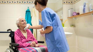 Eine Pflegekraft wäscht eine Patientin.