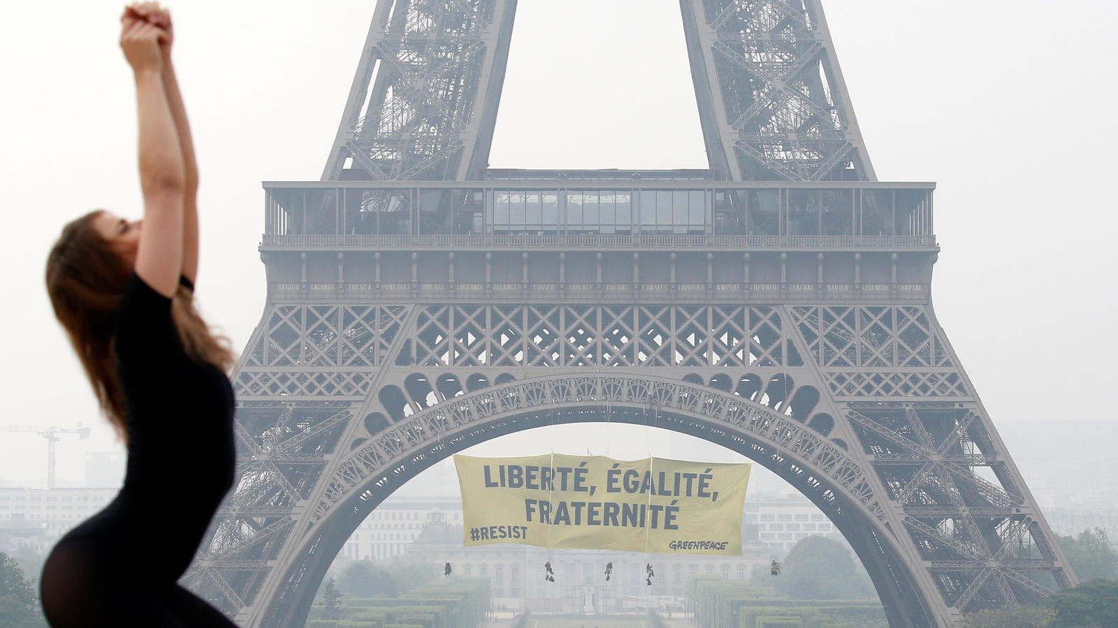A dancer attends a photo shooting as activists from the environmentalist group Greenpeace unfurl a giant banner on the Eiffel Tower which reads "Liberty, Equality, Fraternity" in a call on French citizens to vote against the National Front (FN) presi