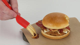 HANDOUT - Die von McDonald's zur Verfügung gestellte undatierte Aufnahme zeigt die Demonstration eins neues Zubehörteils der Fastfood-Kette, die «Frork», als Teil einer Werbe-Kampagne, um neue Burger-Kreationen zu bewerben. Laut McDonal's hat die «Frork» eine Öffnung, die es erlaubt, Pommes-Frittes als Zinken einer Gabel nutzen zu können. (ACHTUNG: Nur zur redaktionellen Verwendung in Zusammenhang mit der Berichterstattung über das genannte Produkt und nur bei vollständiger Nennung der Quelle: «McDonald's/AP/dpa») Foto: Uncredited/McDonald's/AP/dpa +++(c) dpa - Bildfunk+++